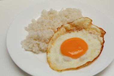 Güneşte pişmiş yumurta ve beyaz tabakta pilav. Beyaz arkaplanda izole