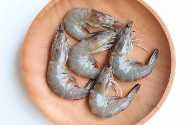 Uncooked whiteleg shrimps or Litopenaeus vannamei, on a wooden plate. Isolated on white background clipart