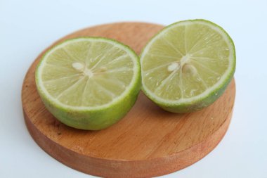 Halves of Green Lime, on wooden base, isolated on white background