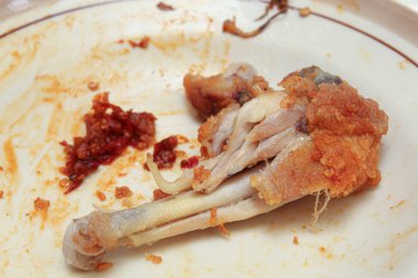 Yemek artıkları ya da yiyecek atıkları. Tabakta kızarmış tavuk ve acı biber sosu var.