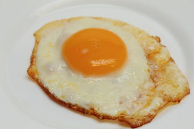 Güneşli tarafı ya da kızarmış tavuk yumurtası beyaz tabakta. Fazla pişmiş, çıtır çıtır.