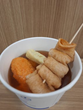 Odeng ya da Kore balık köftesi şişi köfte ve tofu ile birlikte, kağıt kasede, ahşap masada..