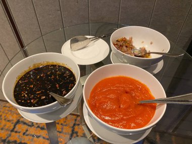 Beyaz kasede çeşitli Endonezya sosu. Acı biber dilimli kalın soya sosu, sambal matah ve acı biber sosu ezmesi.