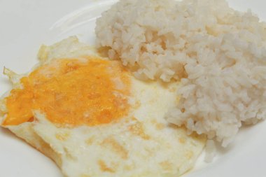 Yumurta ve pilav. Yumurta ters çevrildi ve yumurta sarısı sert pişirildi. Kızarmış tavuk yumurtası. Beyaz bir tabakta