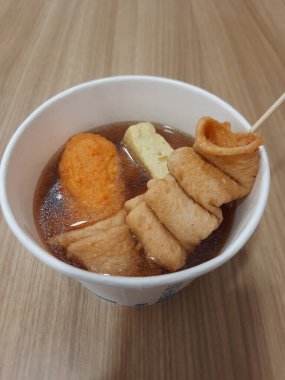 Odeng ya da Kore balık köftesi şişi köfte ve tofu ile birlikte, kağıt kasede, ahşap masada..