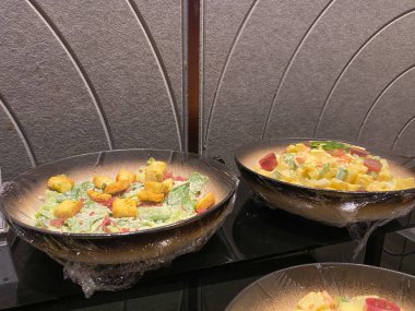 Caesar salad and huzarensla salad served on a bowl, wrapped by plastic. Buffet menu on hotel or restaurant clipart