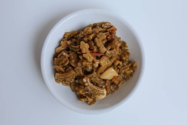 Karıştırılmış acı kavun ya da sotelenmiş kavun beyaz bir tabakta, beyaz arka planda izole edilmiş, üst ya da düz yatıyordu