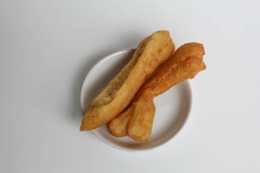 Cakwe or cakue, fried savory cake from Indonesia, on small white plate, isolated on white background, top view or flat lay clipart