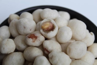 Kacang Atom, snack from Indonesia, made from peanut covered by flour dough then fried. On black bowl, isolated on white background clipart