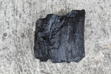 Gri arkaplandaki tahtadan bir parça kömür