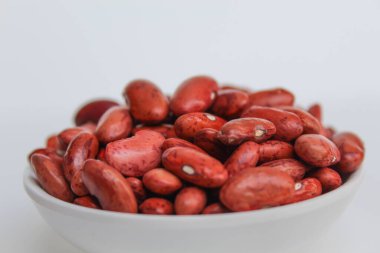 Kırmızı fasulye, bir kasede, beyaz arka planda izole edilmiş.