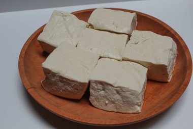 Uncooked white tofu on a wooden plate, isolated on white background clipart