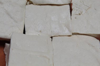 Ahşap bir tabakta pişmemiş beyaz tofu, beyaz arka planda izole, düz ya da üst görünüm