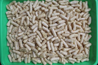 Küçük silindir şeklinde balık krakerleri. Endonezya 'dan atıştırmalık, adı Krupuk ikan tongkol. Yeşil bir tavada düz ya da üst görünüm