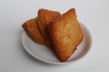 Odading or Bolang-Baling or Pillow Cake, sweet fried bread with sesame seed on top, from Indonesia. On a small plate isolated on background