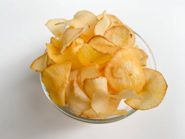 Cassava cipsleri, şeffaf bir kasede, beyaz arka planda izole edilmiş.