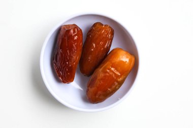 Üç parça Deglet noor veya deglet nur veya hurma veya hurma, küçük bir kasede, beyaz zemin üzerinde izole edilmiş, düz veya üst görünüm
