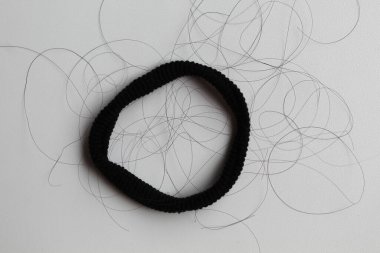 A black hair ties with strands of black hair. Hair loss or hair falling out or hair breakage clipart