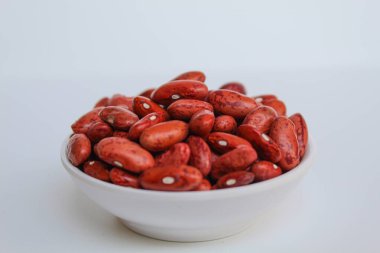 Kırmızı fasulye, bir kasede, beyaz arka planda izole edilmiş.