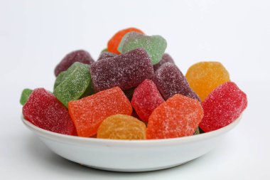 Beyaz arka planda izole edilmiş renkli şeker ya da küçük beyaz tabakta şekerli meyve jölesi.