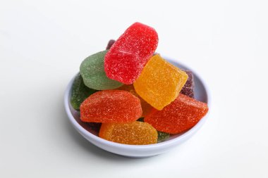 Beyaz arka planda izole edilmiş renkli şeker ya da küçük beyaz tabakta şekerli meyve jölesi.