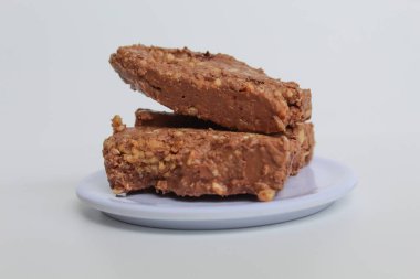 Üç çubuk çikolata ezilmiş fındıkla karıştırılmış, beyaz arka planda izole edilmiş.