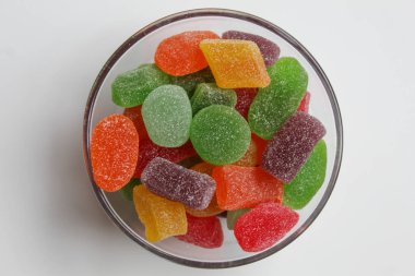 Renkli şekerleme ya da şeffaf kâsede şekerli meyve jölesi, beyaz arka planda izole, düz ya da üst görünümde
