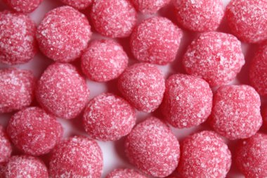 Arkaplan desenli, şekerli, pembe renkli ve top şeklinde, şekerle kaplı. Düz ya da üst görünüm
