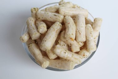 Küçük silindir şeklinde balık krakerleri. Endonezya 'dan atıştırmalık, adı Krupuk ikan tongkol. Şeffaf cam bir kasede, beyaz arka planda izole edilmiş.