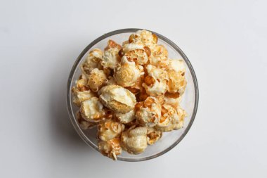 Karamelli patlamış mısır, şeffaf cam bir kasede, beyaz arka planda izole, düz ya da üst görünümde