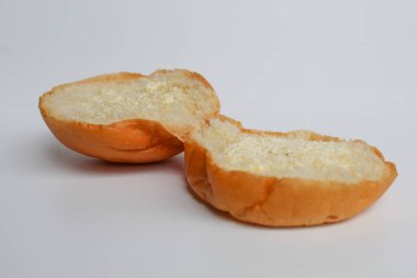 Bir çörek, ikiye bölünmüş, dilimlenmiş, içine krema serpilmiş. beyaz arkaplanda izole