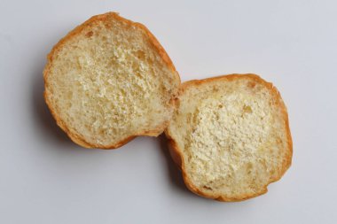 Bir çörek, ikiye bölünmüş, dilimlenmiş, içine krema serpilmiş. beyaz arkaplanda izole