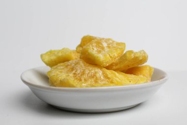 Kurutulmuş ananas tatlısı. Şekerli ve kurutulmuş ananas. Küçük beyaz tabakta. Beyaz arkaplanda izole