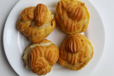 Kremalı puf, beyaz tabakta, beyaz zemin üzerinde izole, düz ya da üst görünüm