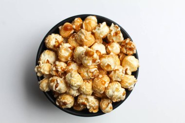 Karamelli patlamış mısır, siyah bir kasede, beyaz arka planda izole edilmiş, düz ya da üst manzara