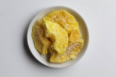 Kurutulmuş ananas tatlısı. Şekerli ve kurutulmuş ananas. Küçük beyaz tabakta. Beyaz arkaplan, düz yatay veya üst görünümde izole edilmiş