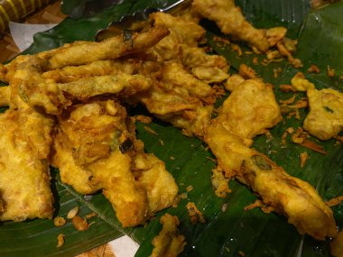 Tempeh fried with dough called mendoan, on banana leaves mat clipart