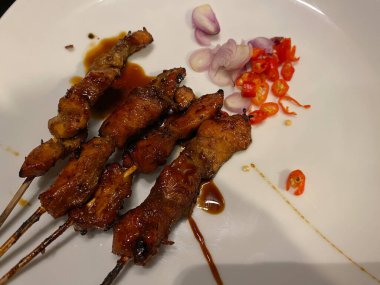 Soya soslu ızgara tavuk, soğan dilimi ve acı biber dilimleri. Bir porsiyon. Arkaplan olarak beyaz plaka