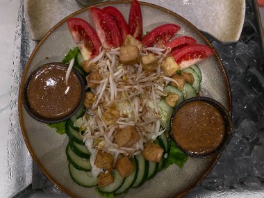 Gado-gado is traditional salad from Indonesia, made from cooked vegetables, tofu cuts, mung bean sprouts and peanut sauce dressing clipart