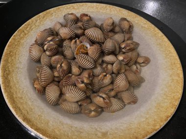 Buharda pişmiş Tegillarca granosa, Anadara granosa, gemi midyesi, kan midyesi veya kan midyesi, bir tabakta