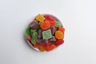 Renkli şekerleme ya da küçük beyaz tabakta meyveli jöle, beyaz arka planda izole, düz ya da üst görünümde