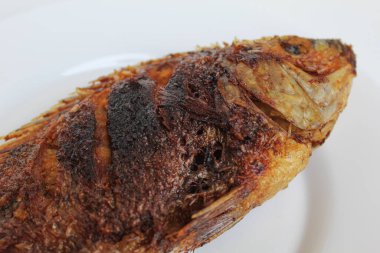 Beyaz bir tabakta kızarmış gurami balığı, beyaz arka planda izole edilmiş.