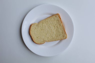 Beyaz tabakta bir dilim beyaz ekmek, beyaz zemin üzerinde izole, düz ya da üst görünüm