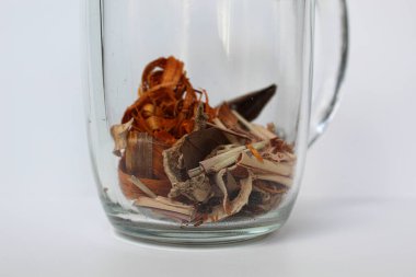 Wedang Uwuh, or Javanese herbal drink, inside transparante glass, isolated on white background. Ingredients before brewed of Indian redwood, dried ginger, lemongrass and cardamom clipart