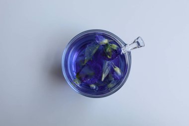 Taze kelebek yaprağı ya da klitoria ternatea çayı. Mor renkli su. Şeffaf camın içinde, beyaz arkaplanda izole edilmiş, düz ya da üst görünümde
