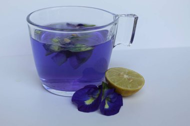 Brewed fresh butterflypea flower petals, or Clitoria ternatea tea. Purple color water. Inside transparent glass, isolated on white background clipart