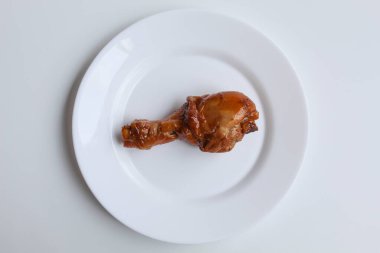 Ayam Kkapap, ya da tatlı soya sosuyla pişirilmiş tavuk. Beyaz tabakta bir tavuk budu, beyaz arka planda izole, düz ya da üst görünümde