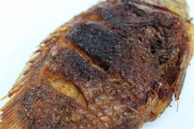 Beyaz bir tabakta kızarmış gurami balığı, beyaz arka planda izole edilmiş.