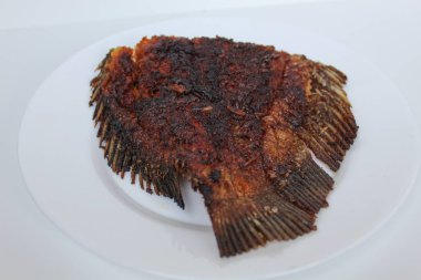 Izgara gurami balığı kuyruğu, beyaz bir tabakta, beyaz arka planda izole edilmiş.