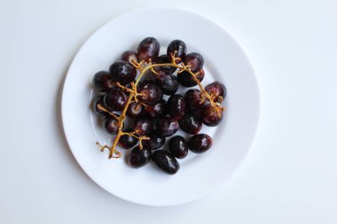 Koyu mor ya da siyah üzümlü, saplı, beyaz plakalı, beyaz arka planda izole, düz ya da üst manzaralı